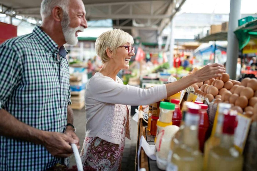 Happy senior couple with basket at the local market